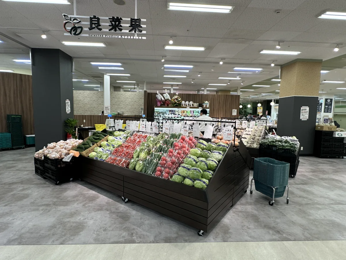 良菜果の看板と、トマトや葉物野菜が並ぶイオン福岡東店の売場